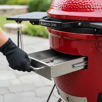 Hand pulling out the patented slide-out ash drawer from a Kamado Joe grill